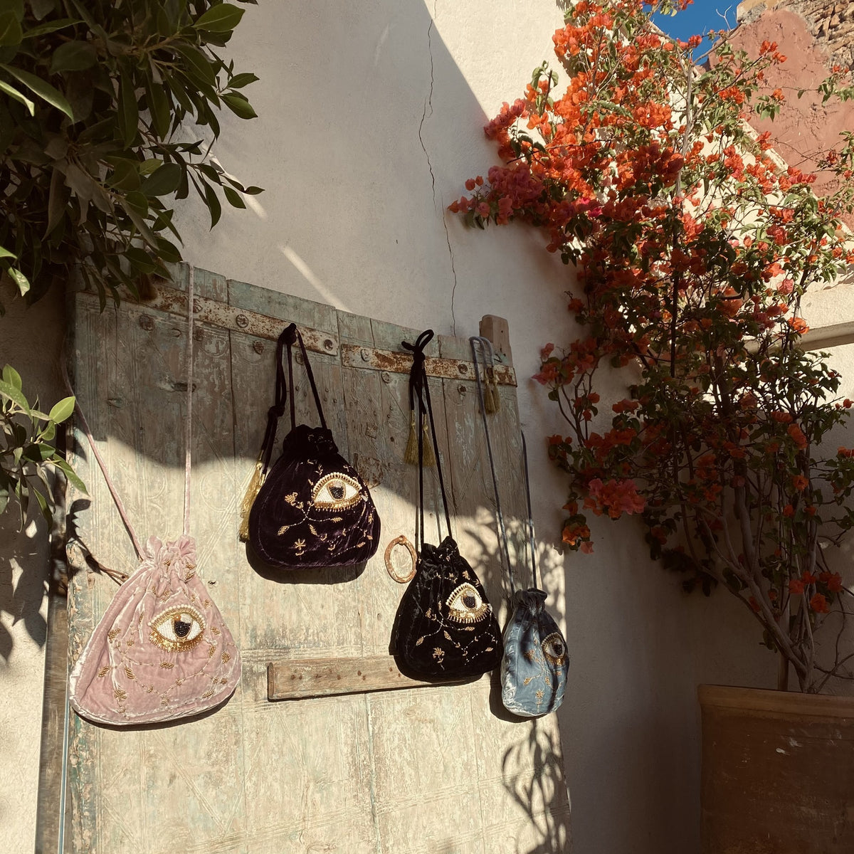 Imagine Pouches hanging on a white wall in Ibiza, next to a bougainvillea